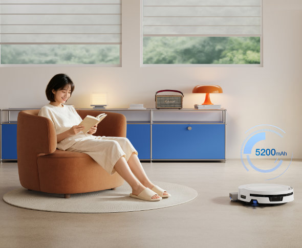 ECOVACS DEEBOT T90 MAX OMNI – robot odkurzająco-mopujący pokazana kobieta na fotelu czytająca i robot odkurzający